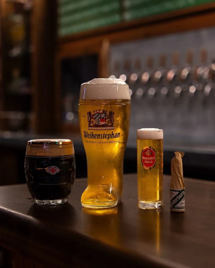 Beers in glasses, including a boot glass, and Underberg on a bar.