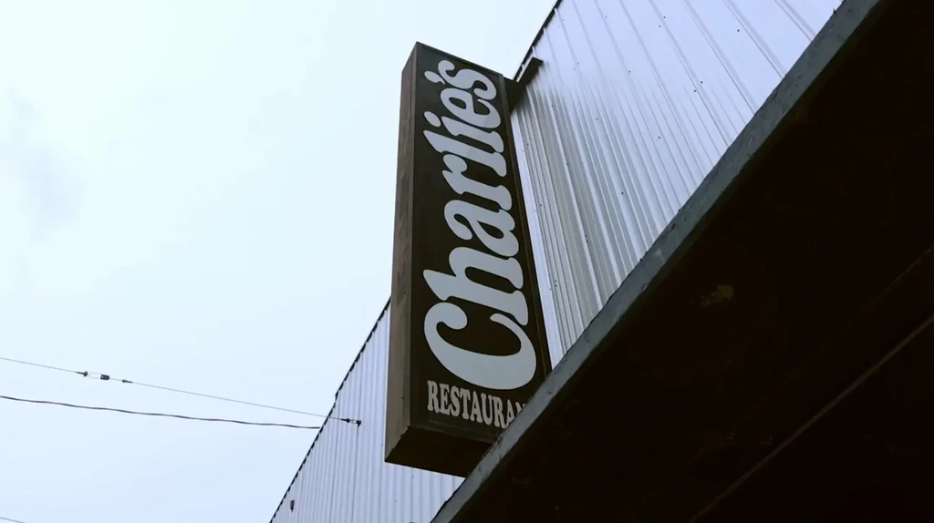 Low-angle view of Charlie's RESTAURANT sign on a corrugated building.
