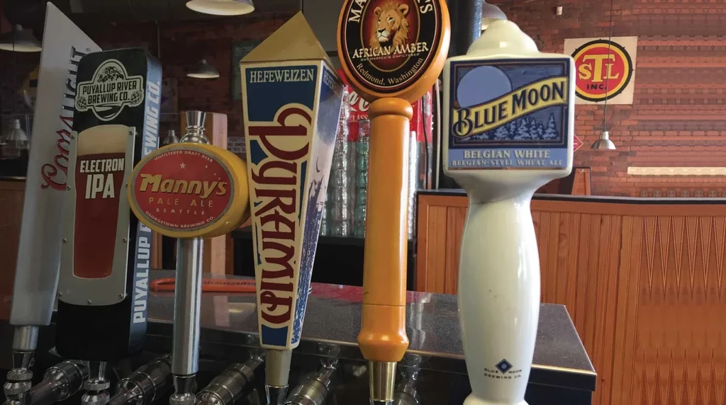 Close-up of a row of different beer tap handles on a bar.