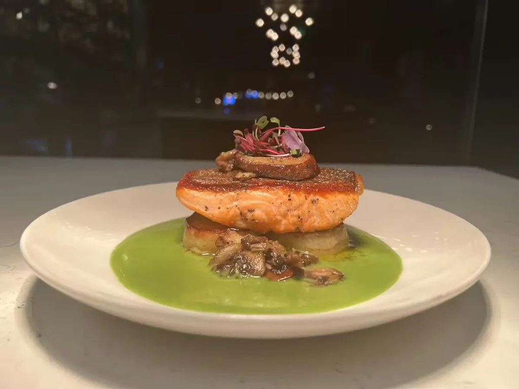 Seared salmon, potato rounds, green sauce, mushrooms, and microgreens.