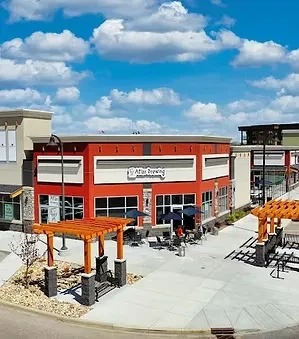 Atlas Brewing's red building, patio, and pergolas on a sunny day.