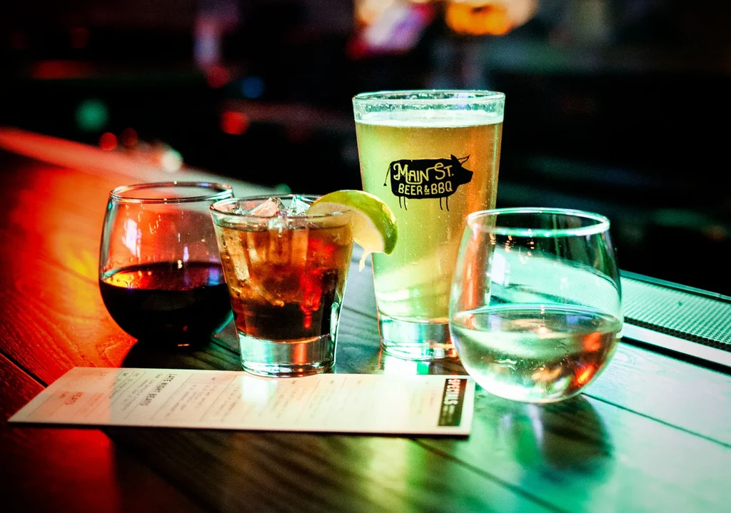 Red wine, cocktail, pig-logo beer, white wine on a dimly lit bar.