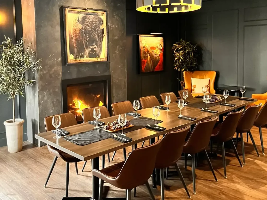 Upscale private dining room with a long set table and fireplace.