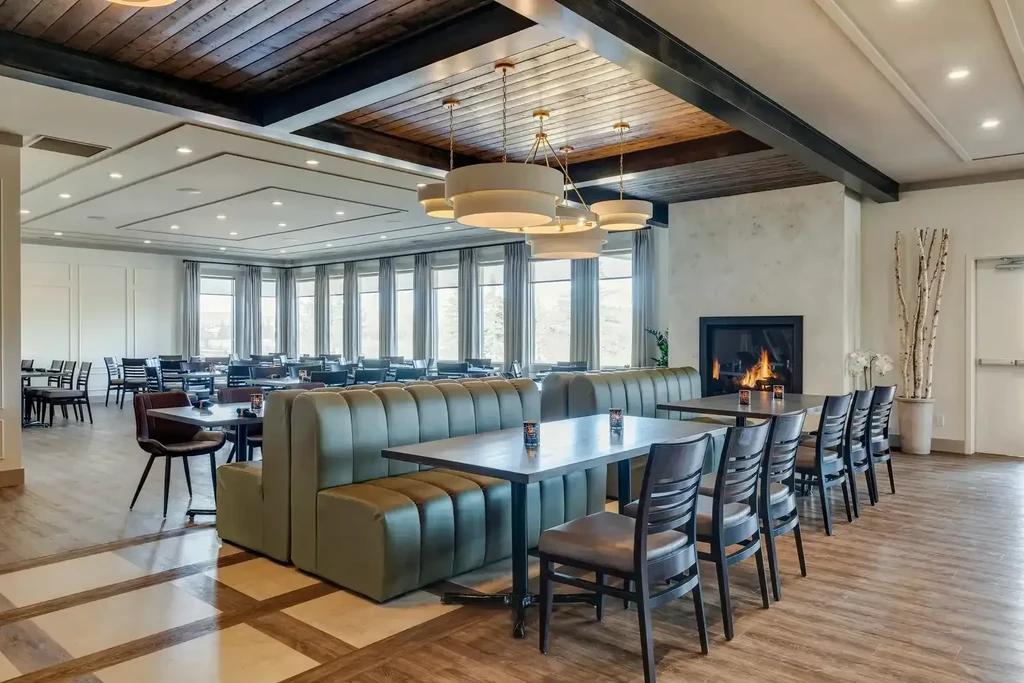 Modern rustic restaurant dining area with olive-green booths and fireplace.