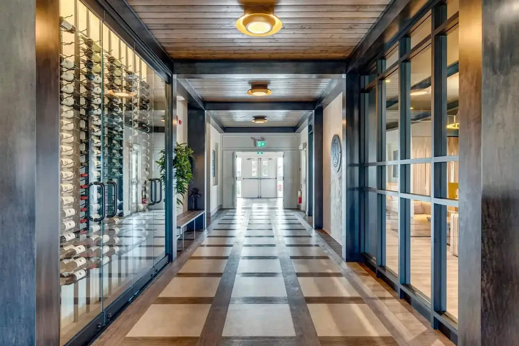 Modern hallway with glass wine cellar and adjacent lounge.