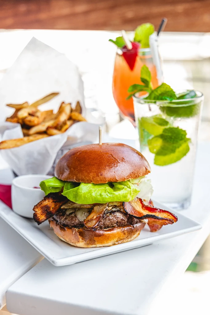 Gourmet burger with fries and two assorted drinks.