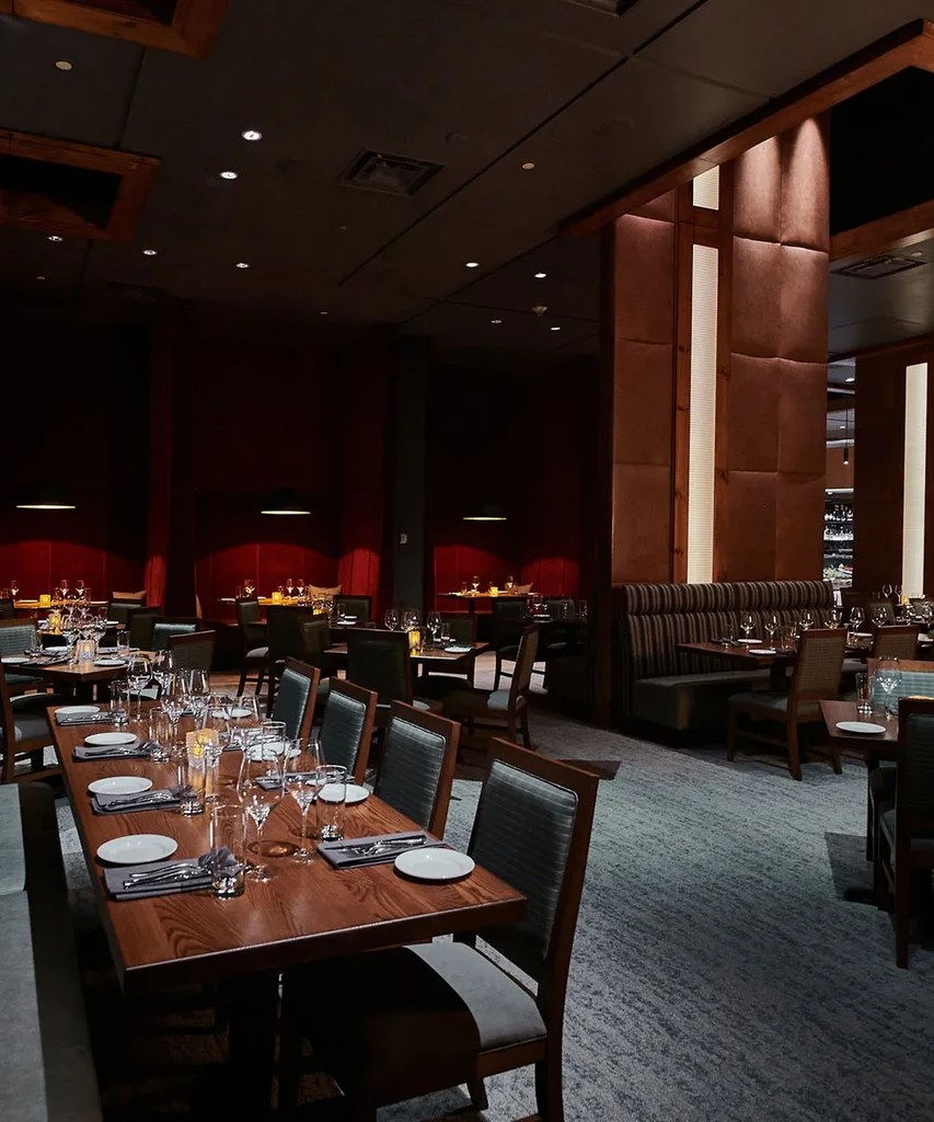 Elegant red-walled restaurant interior with dim lighting and set tables.