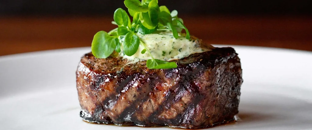 Caramelized grilled steak with melting herb butter and greens.