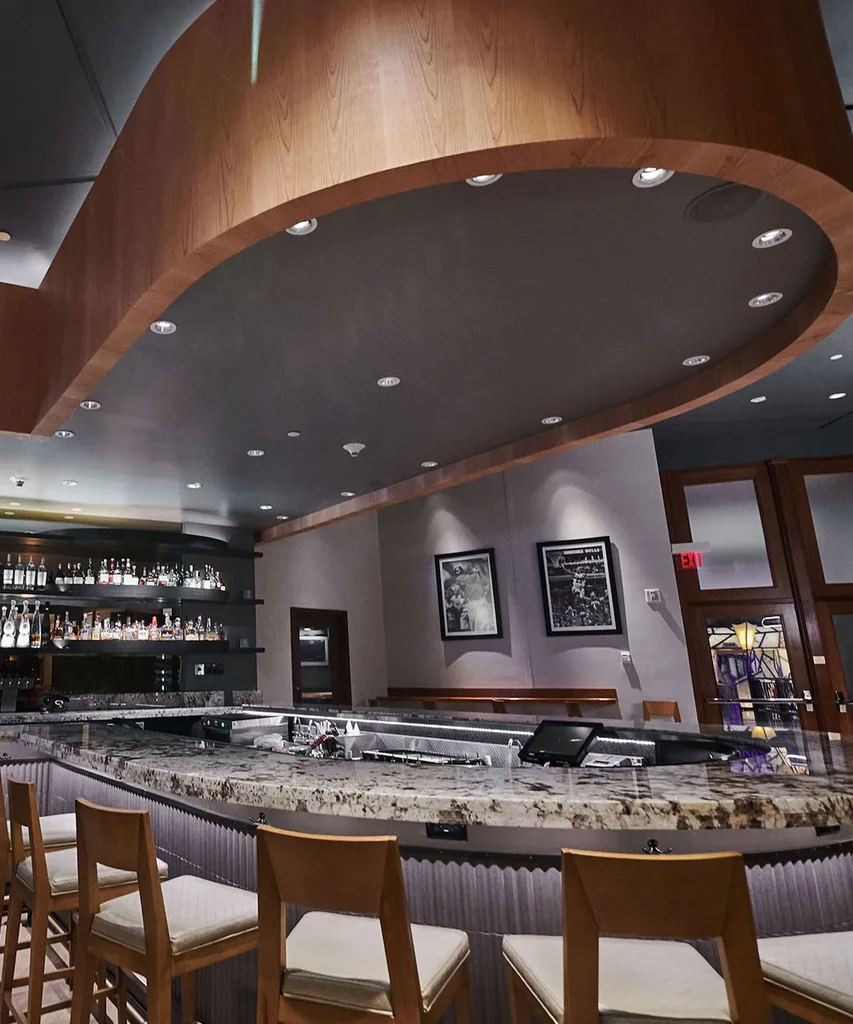 Empty, modern bar with a curved counter and stocked liquor shelves.