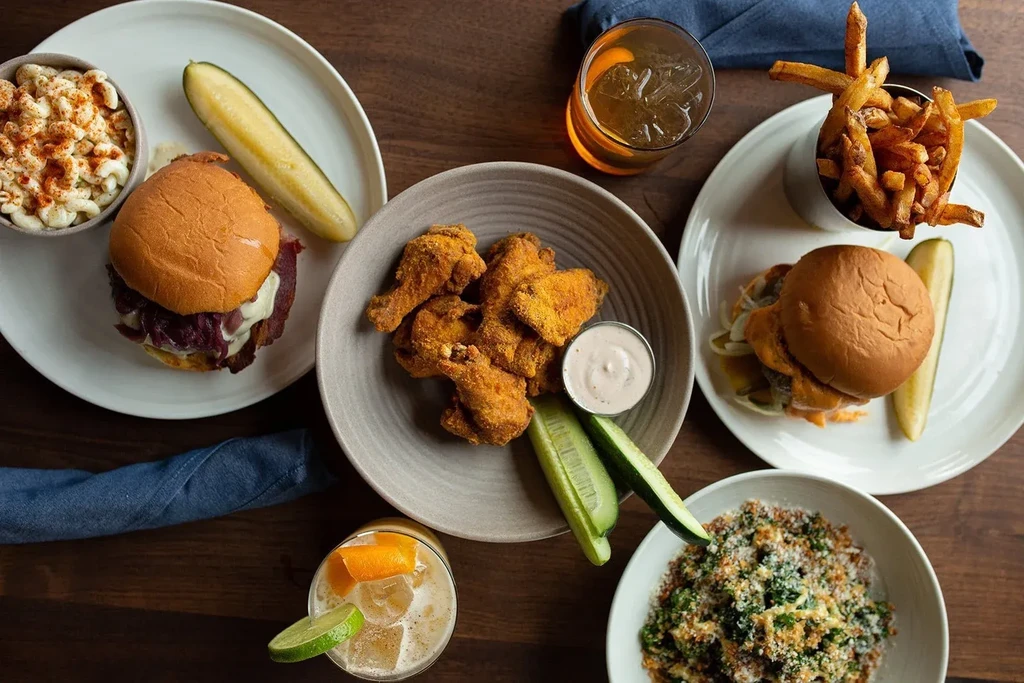 Overhead shot of burgers, chicken, fries, mac and cheese, salad, cocktails.