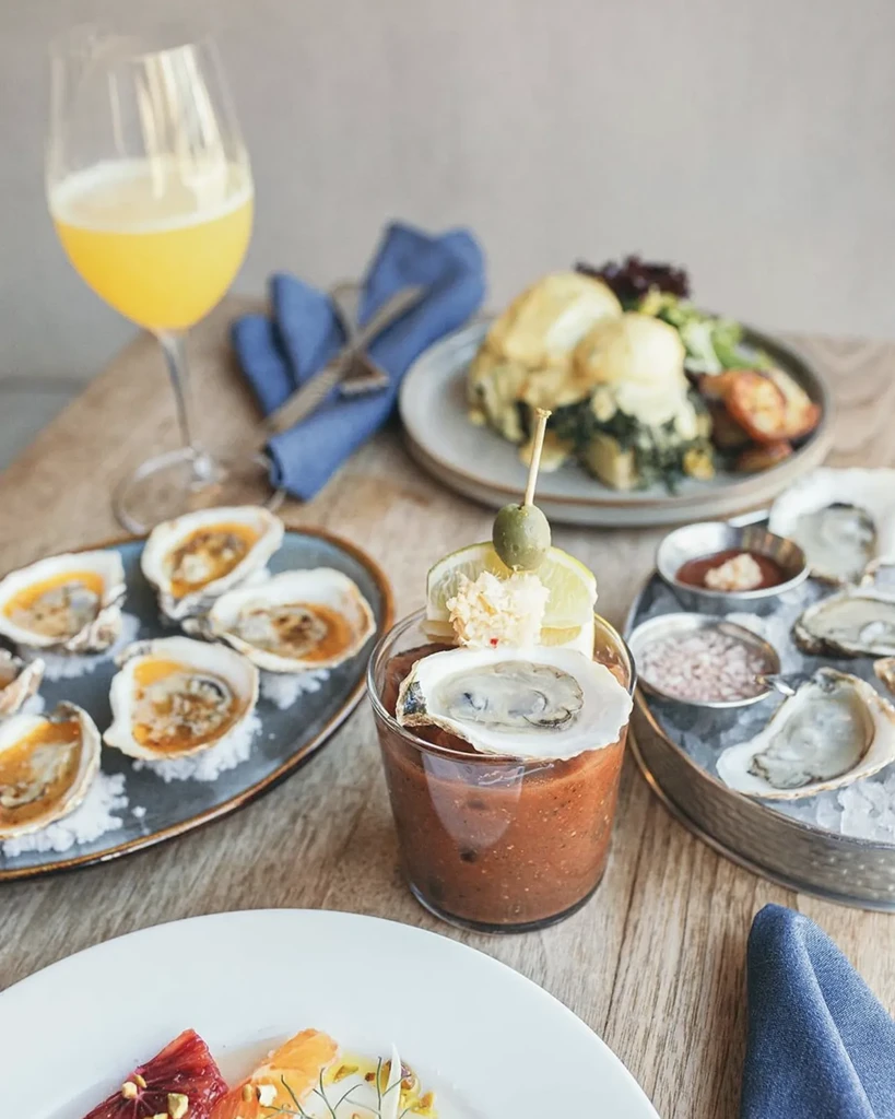 Elegant brunch spread with oysters, a Bloody Mary, and Eggs Benedict.