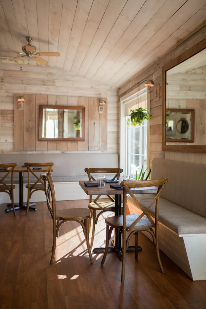 Empty rustic restaurant with wooden walls and set tables.