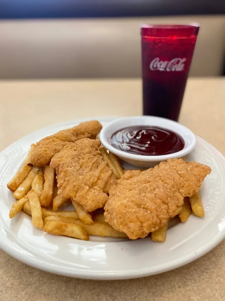 Golden chicken tenders, french fries, dipping sauce, and Coca-Cola.