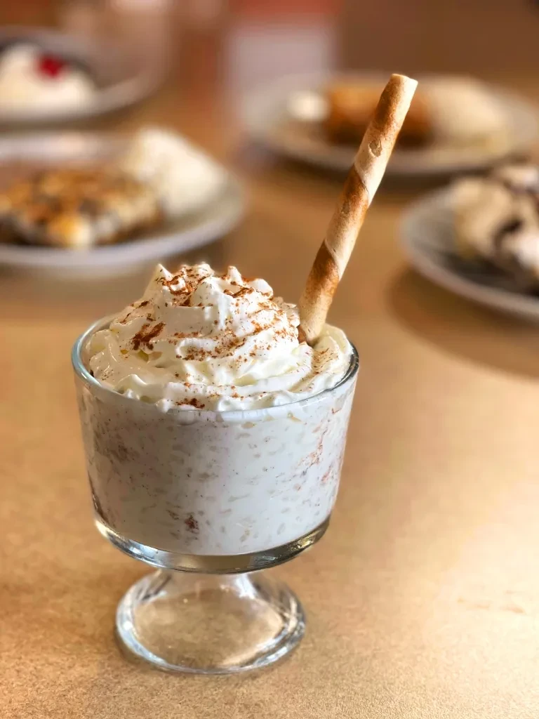 Close-up creamy dessert in glass, whipped cream, cinnamon, wafer stick.