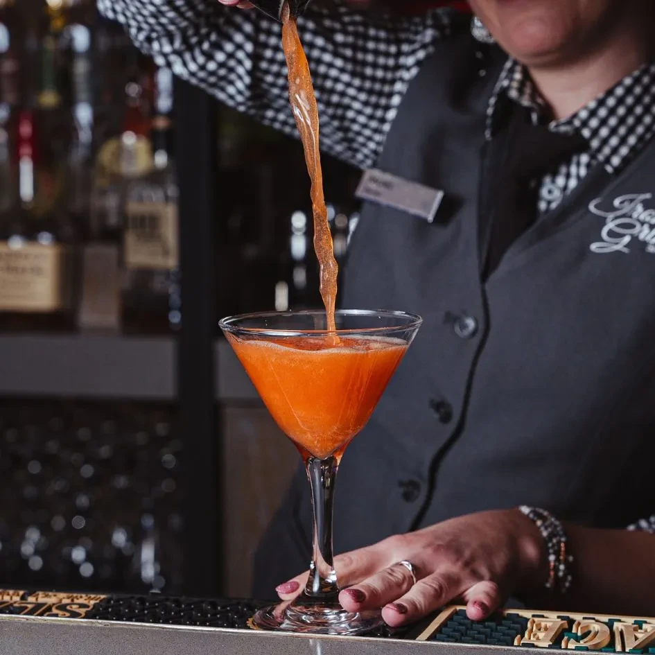 Bartender Mandi pours an orange drink into a martini glass at Trace Grill.
