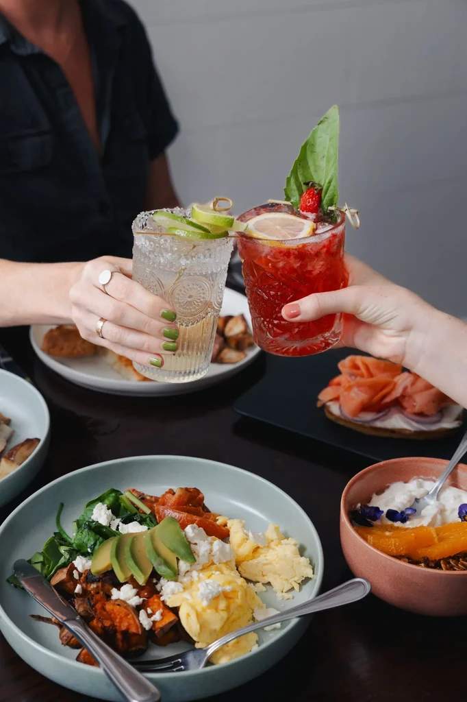 Colorful brunch with eggs, yogurt, salmon, and toasting cocktails.