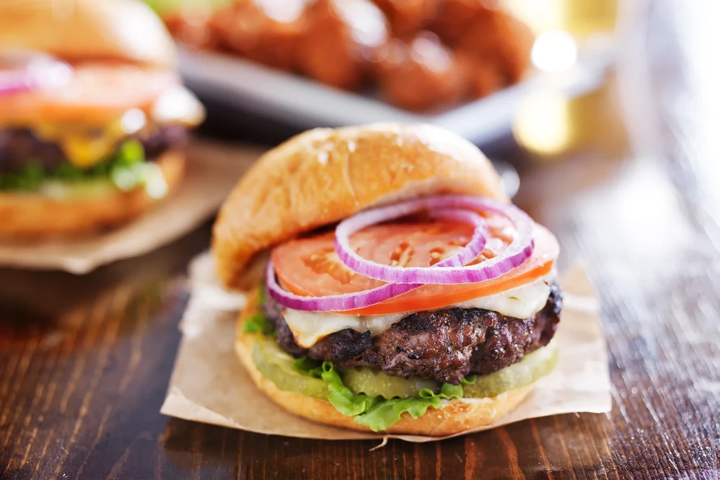 Cheeseburger with patty, melted cheese, lettuce, tomato, pickles, and onion.
