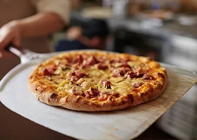 Freshly baked pizza with melted cheese and cured meats on a silver peel.