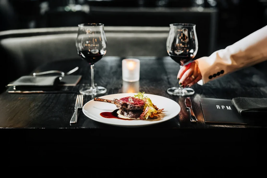 Gourmet dish with red wine and candle at a restaurant table.