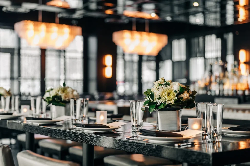 Dining table set with plates, flowers, candles, and chandeliers.