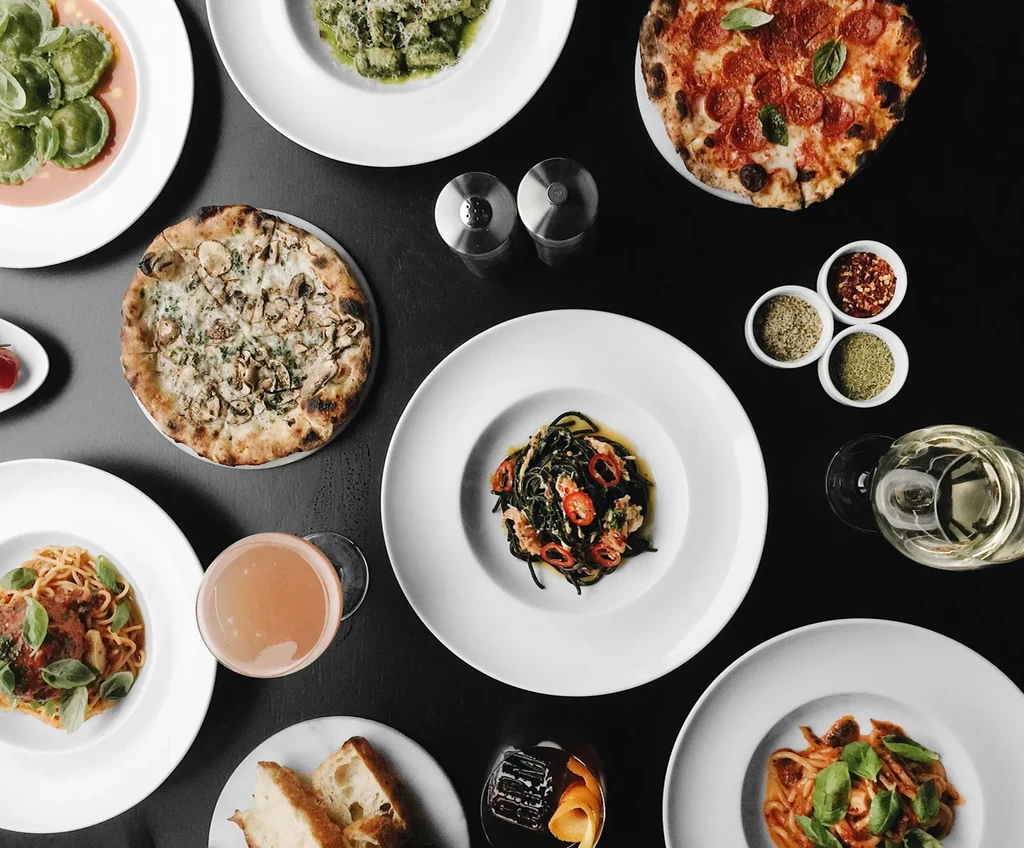 Top-down view of a dark table laden with various Italian dishes.