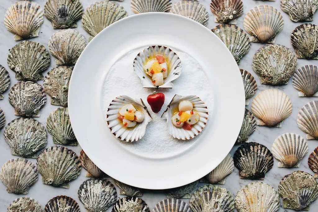 Scallop dishes garnished with fruit, chives, and a heart-shaped object.
