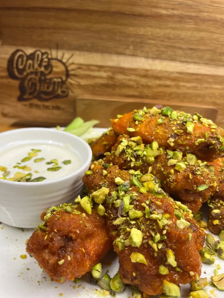 Chicken wings with pistachios and a white dipping sauce.
