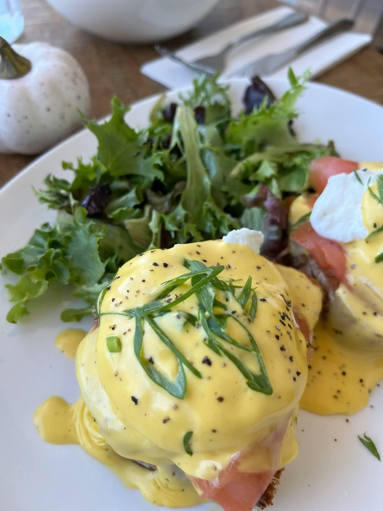 Smoked salmon eggs benedict with hollandaise sauce and a side salad.