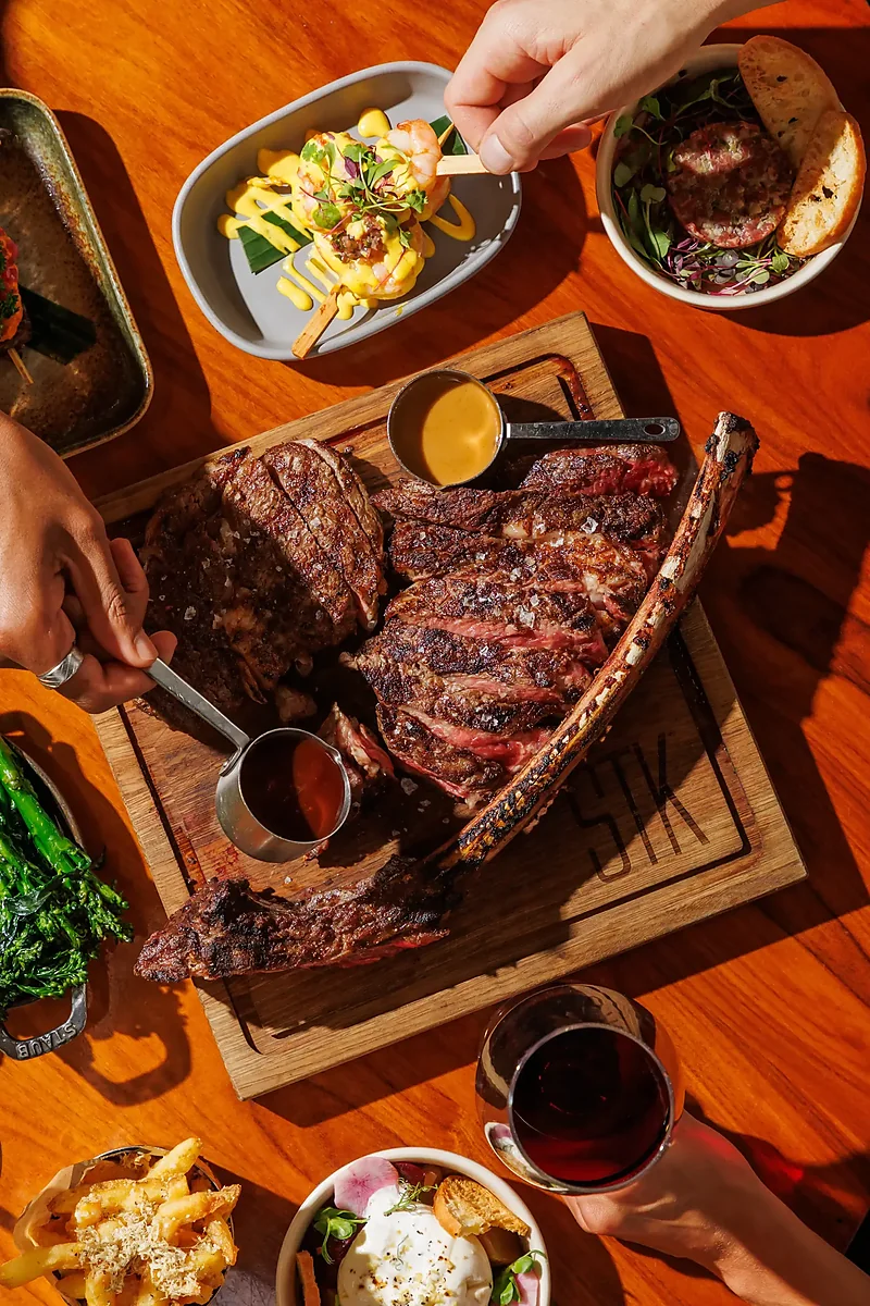 Overhead view of tomahawk steak, shrimp, truffle fries and wine