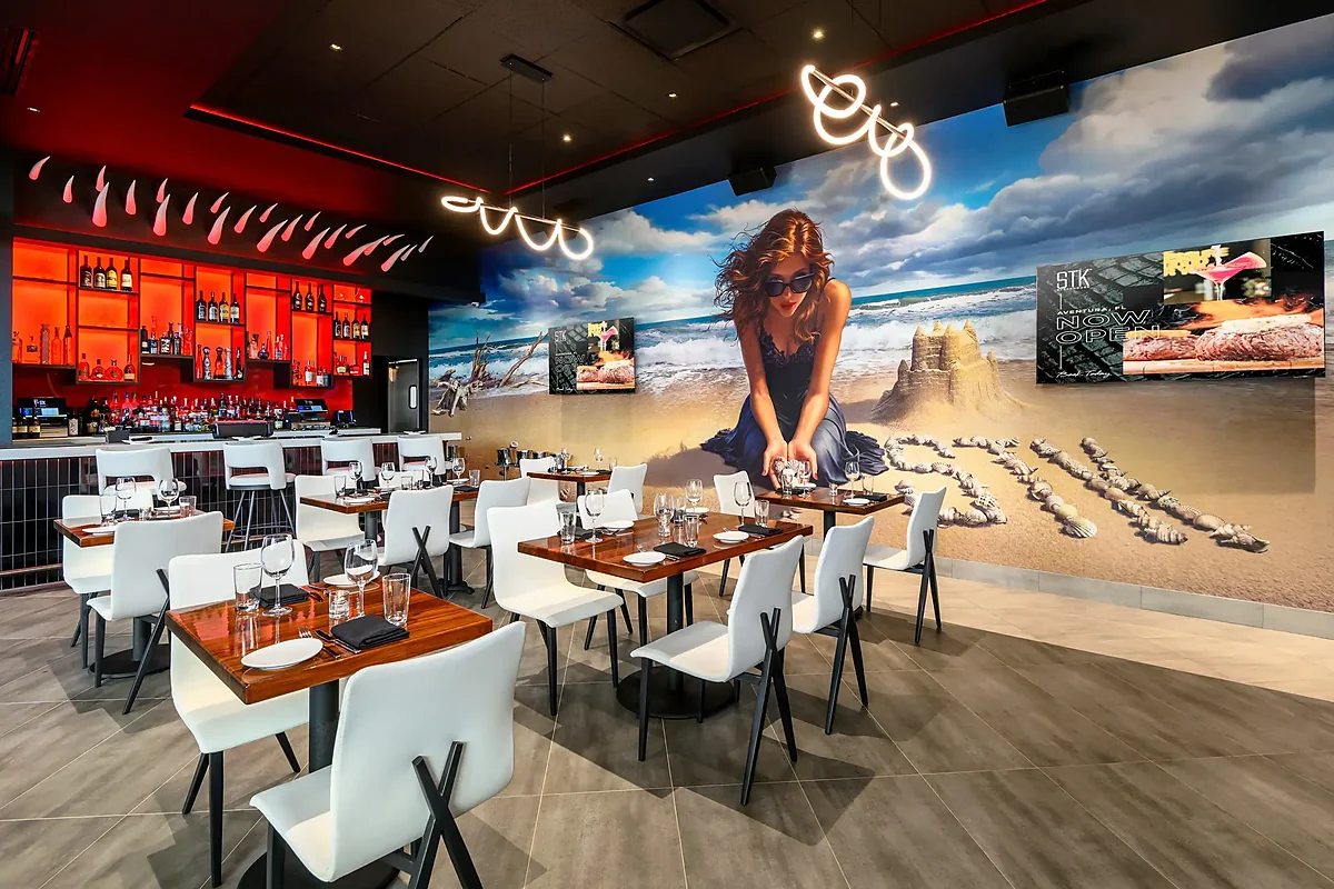 Dining room with beach mural, white chairs and red-lit bar