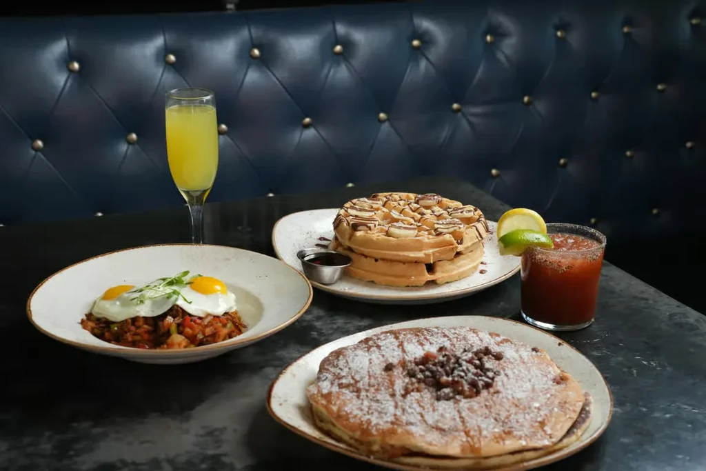 Breakfast and brunch dishes are served on a dark table.