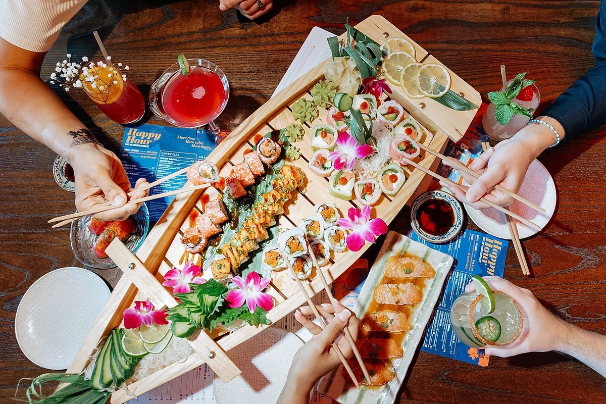 Overhead table of shared sushi boat, sashimi and mixed cocktails
