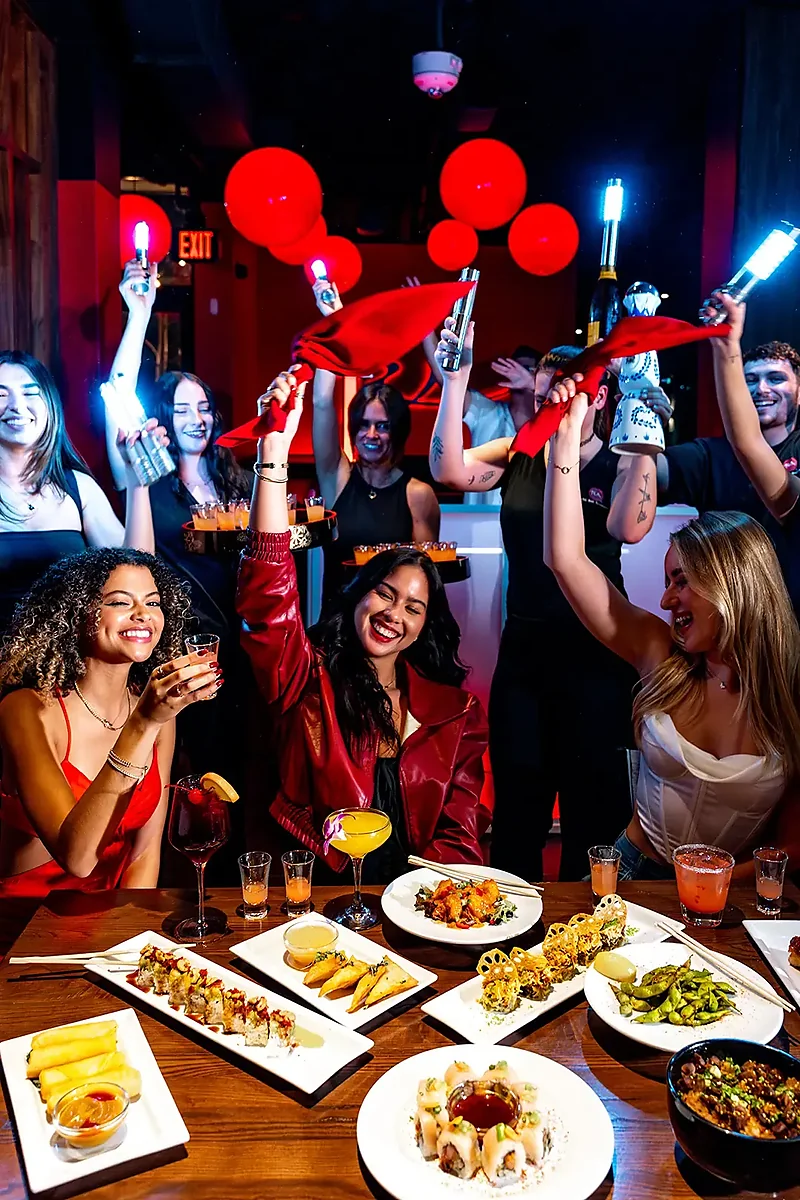 Group at table with sushi platters and cocktails in red-lit dining room