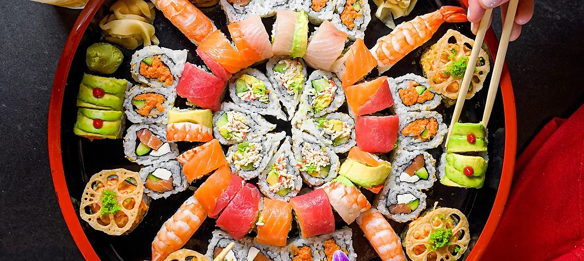 Large round platter of assorted nigiri and maki sushi rolls