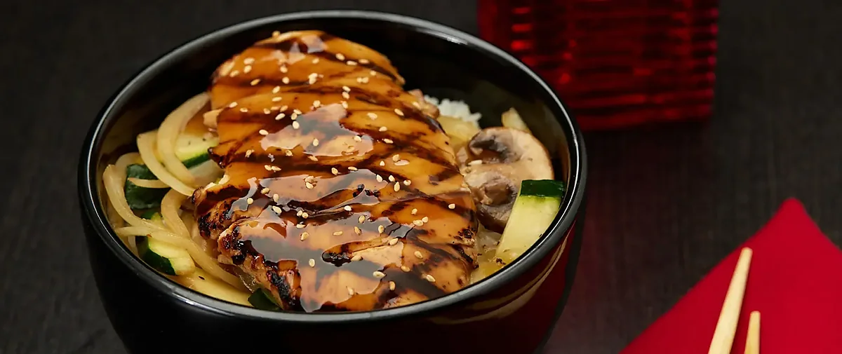 Teriyaki chicken bowl with noodles, zucchini and mushrooms in black bowl