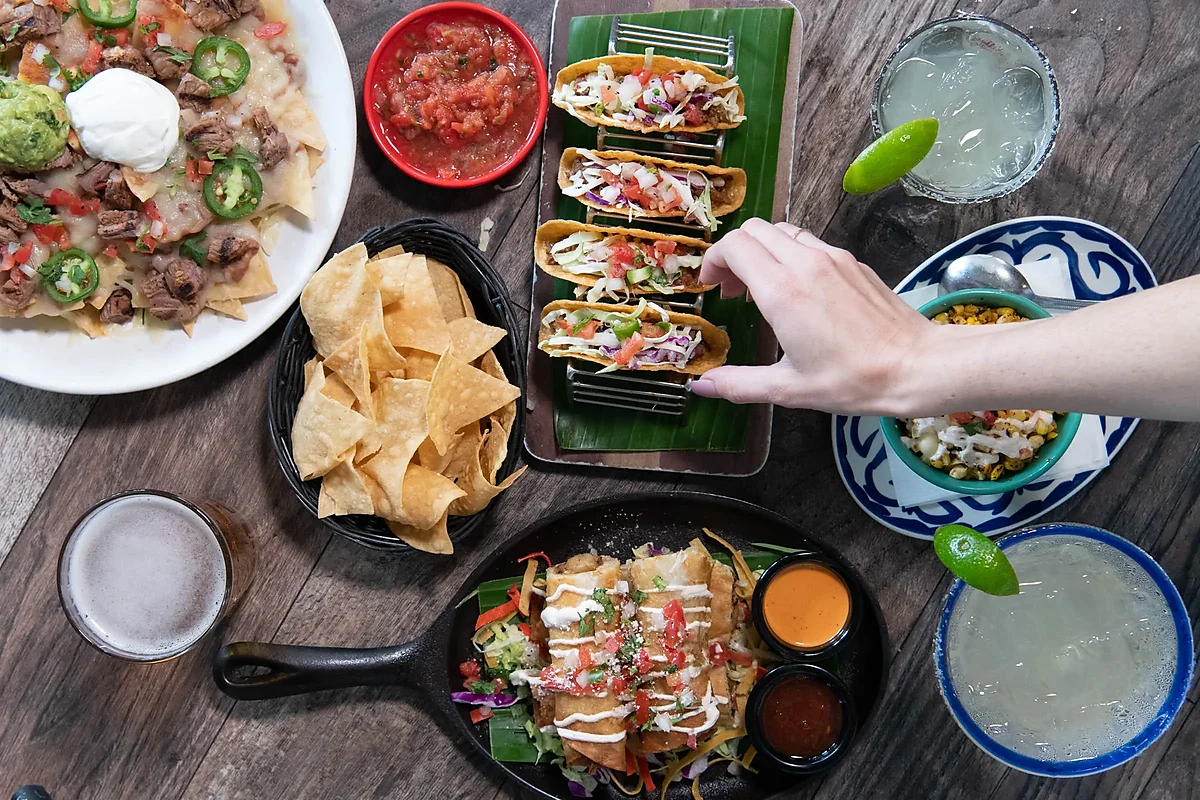 Nachos, tacos, flautas and chips with margaritas on wooden table