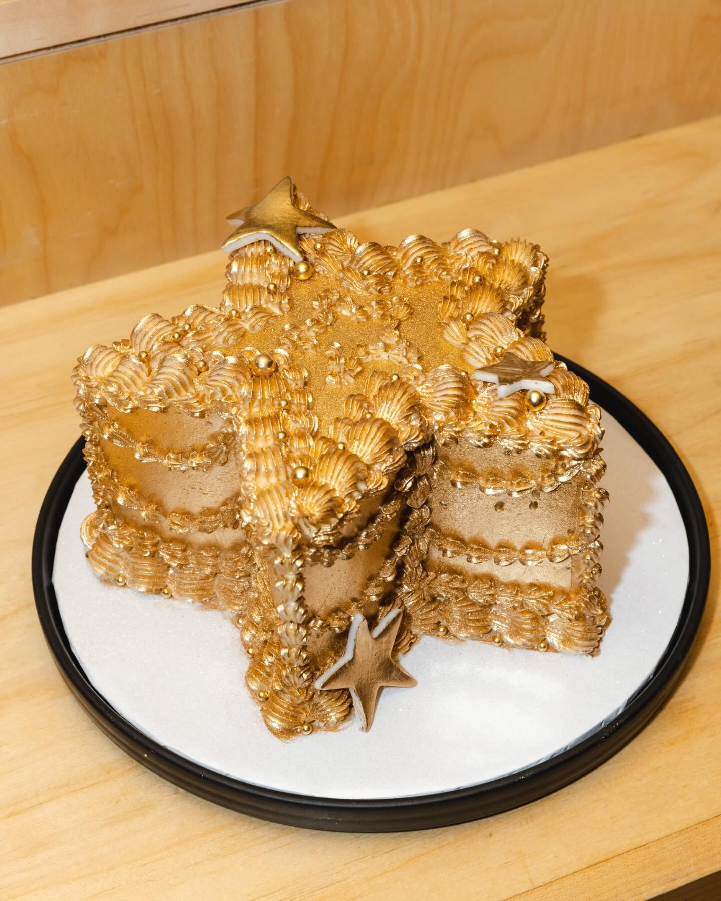 Gold, star-shaped cake with elaborate frosting and star decorations.