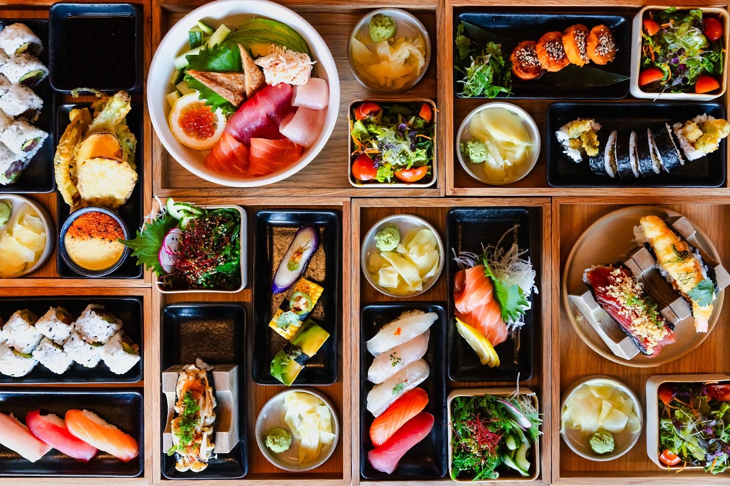 Japanese bento meal with assorted sushi, sashimi, tempura, and salads.