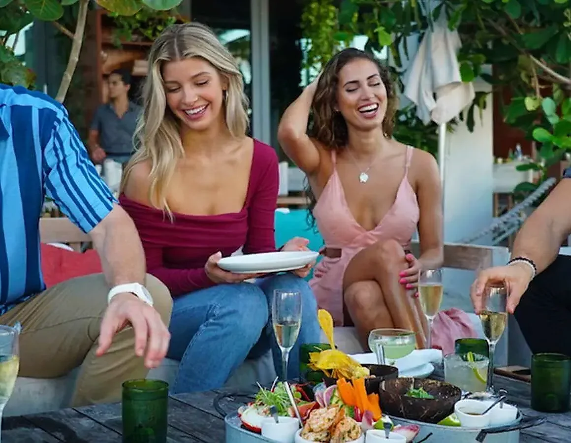 Group seated outdoors with shared seafood platter and sparkling wine