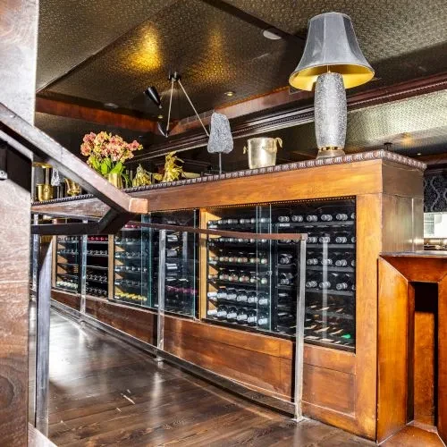 A long wooden wine cabinet with bottles behind glass panels.