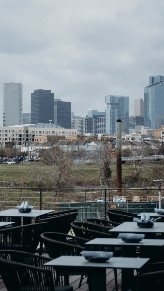 Restaurant patio overlooking a cityscape on a cloudy day.