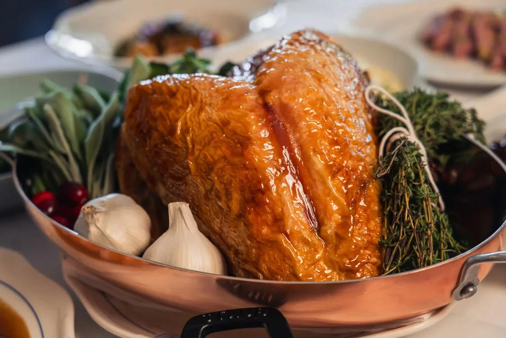 Roasted turkey in a copper pan with herbs, garlic, and berries.