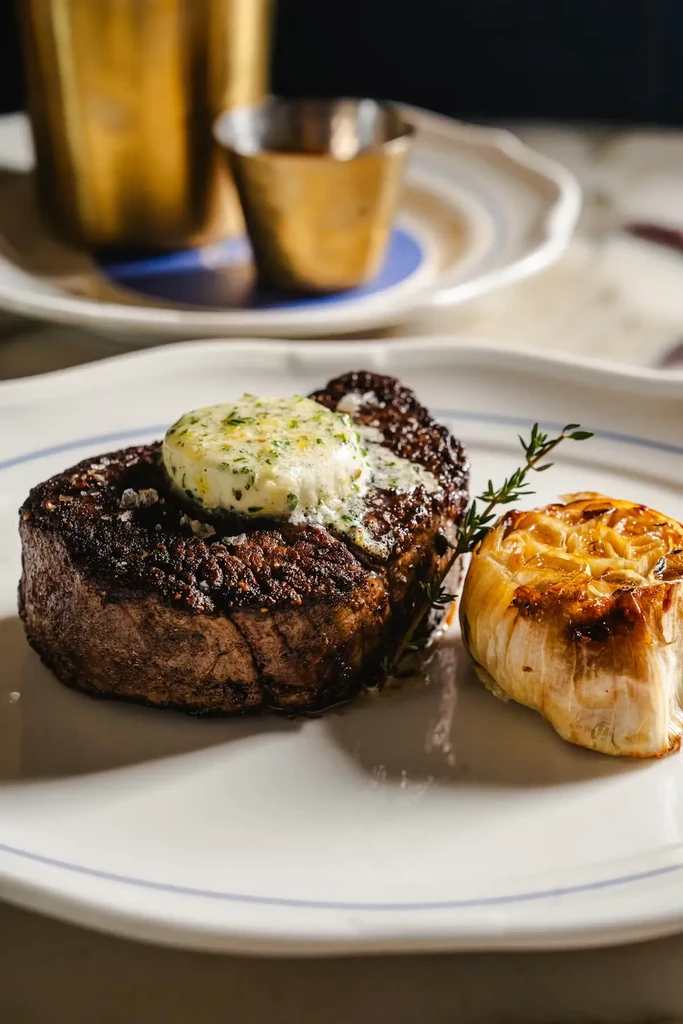 Steak with melting herb butter, roasted garlic, and thyme.