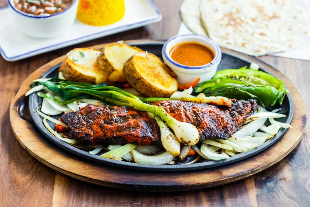 Sizzling fajita or similar dish with grilled meat and vegetables.