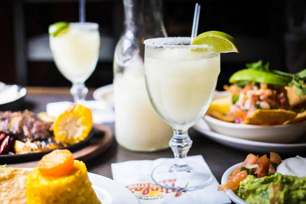 Table with margarita, nachos, fajitas, and other Mexican food.