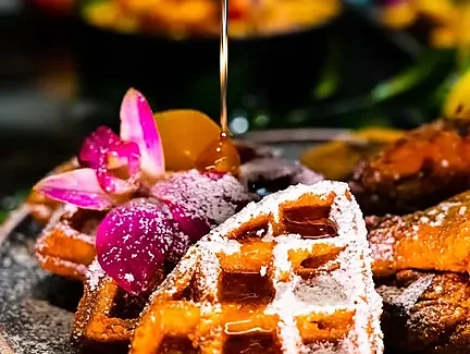 Syrup poured over peach cobbler waffle dusted with powdered sugar