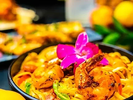 Cajun shrimp pasta topped with grilled shrimp and orchid garnish
