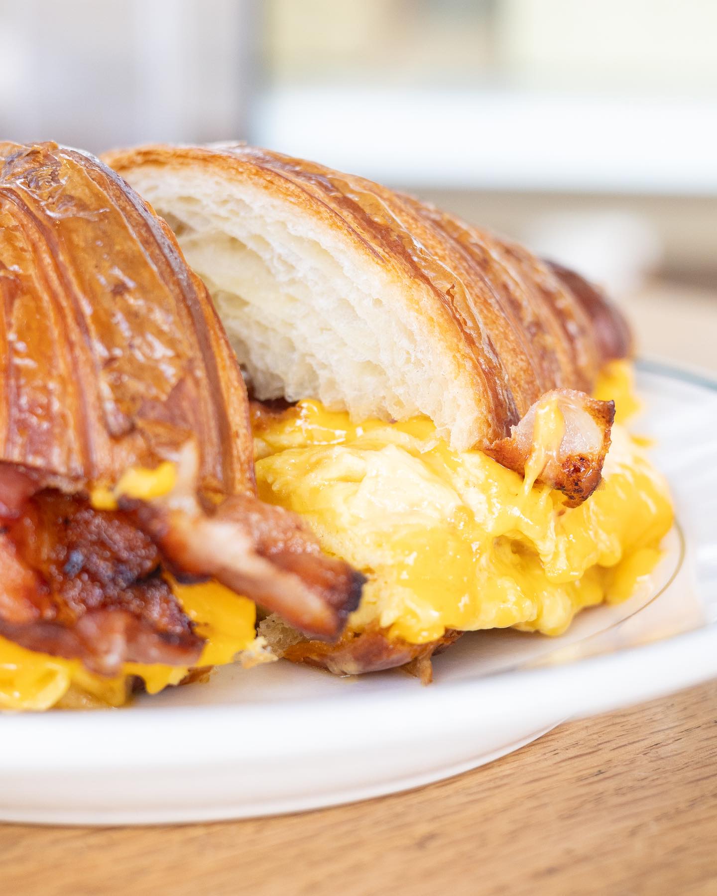 Croissant sandwich filled with scrambled egg, bacon, and melted cheese.