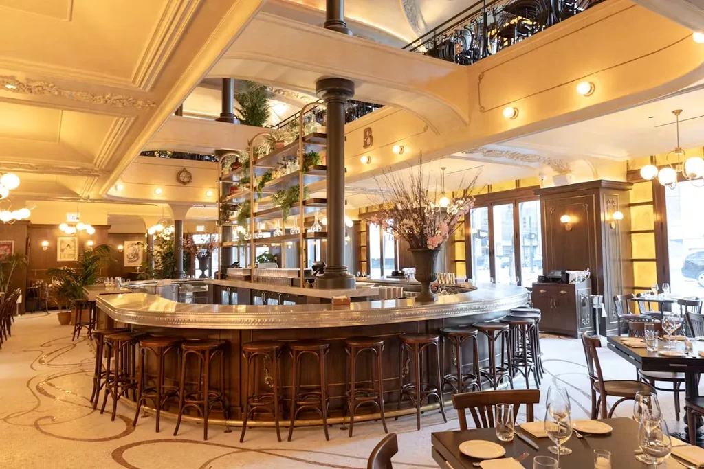 Luxurious restaurant interior with an elegant oval bar and floral arrangements.