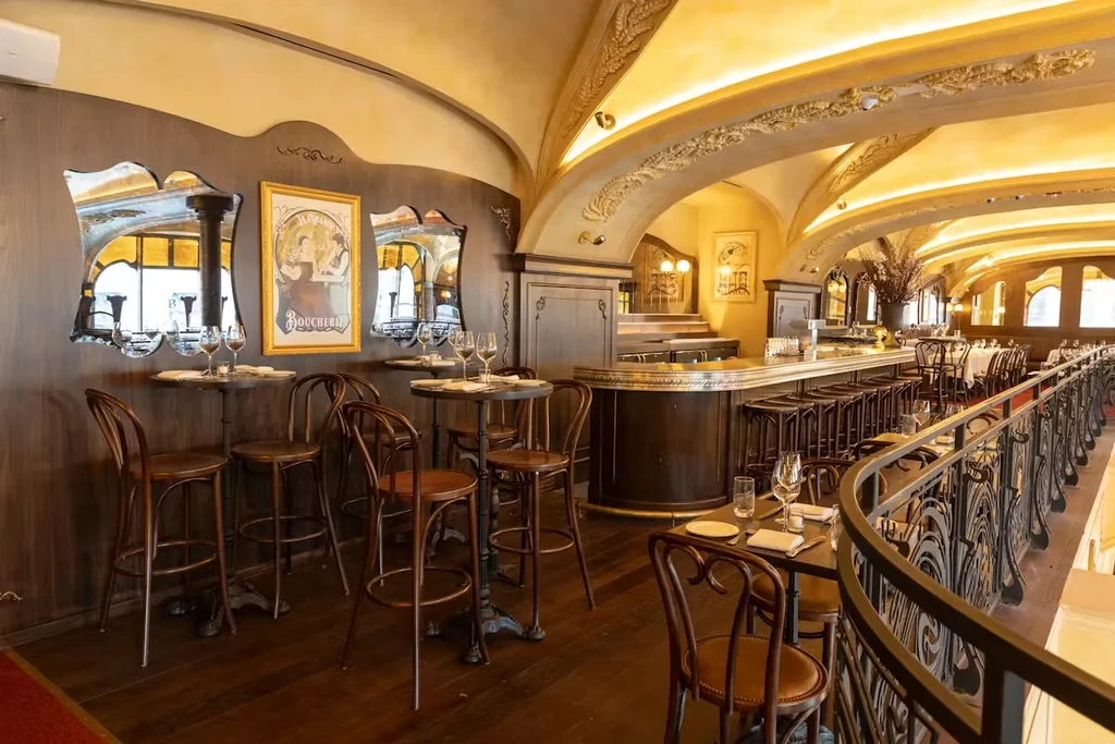 Elegant, empty restaurant with a bar, tables, and arched gold ceiling.